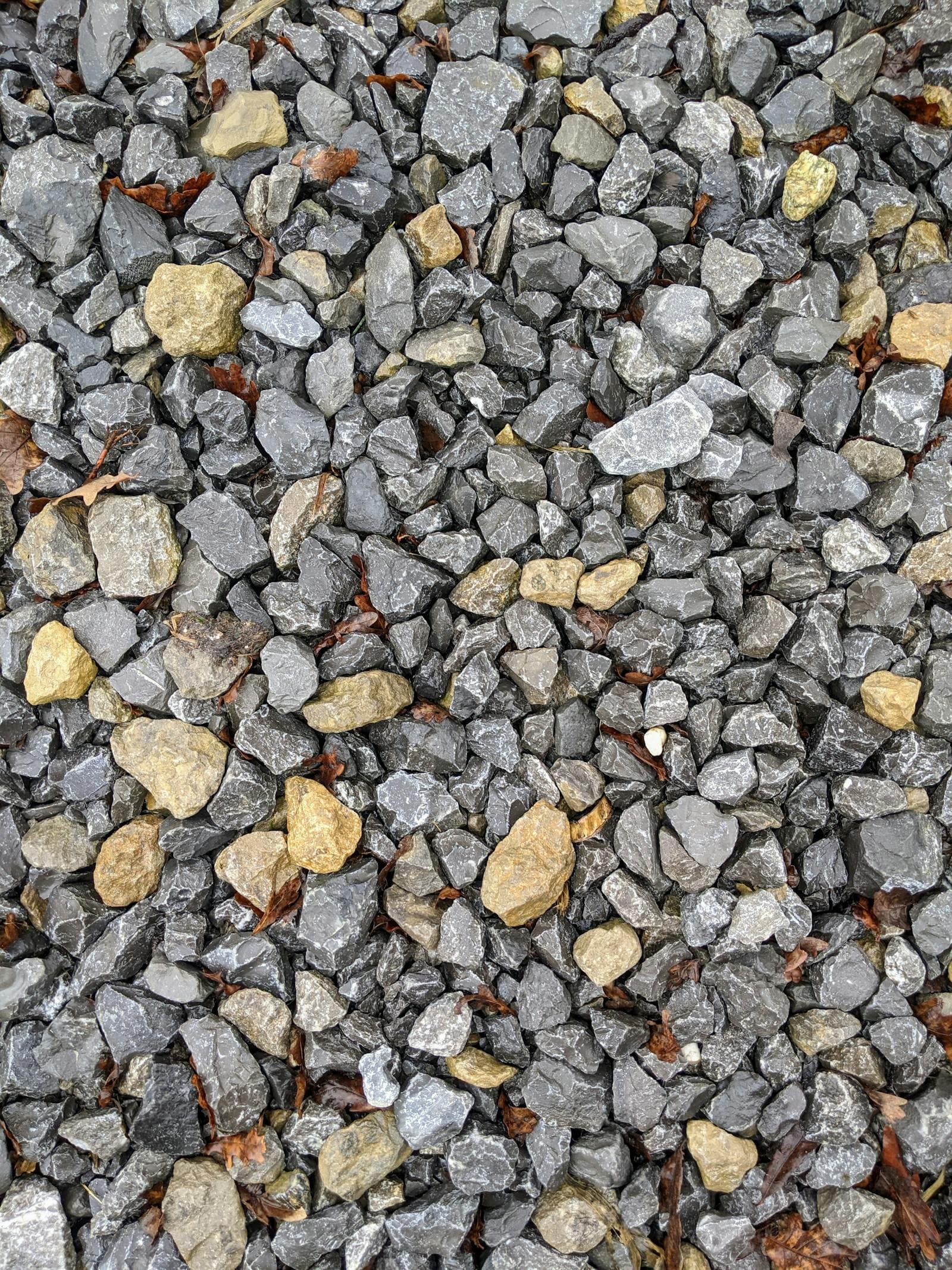 Close-up of angular grey and tan crushed rock road base of the kind produced by crushing concrete on site